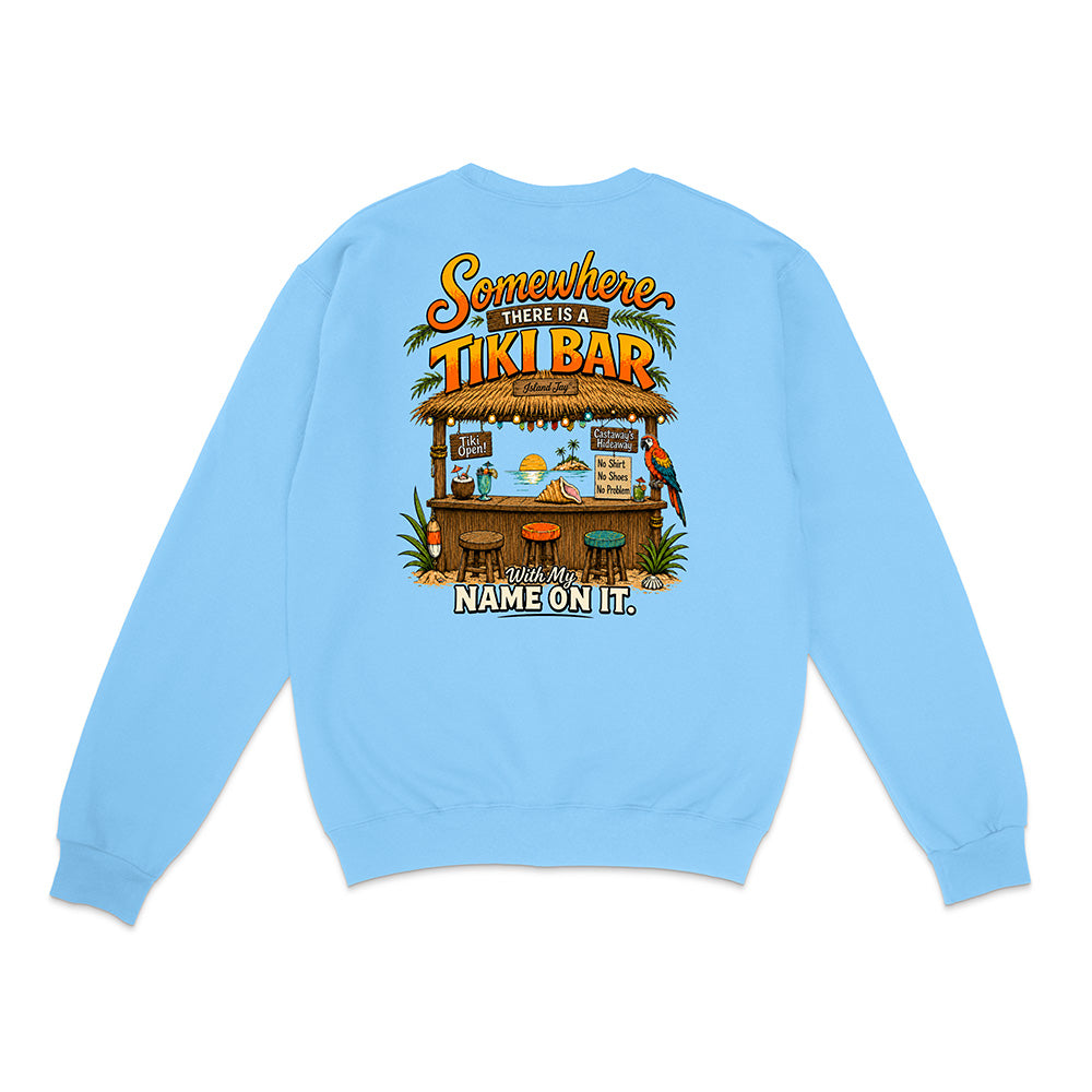 A light blue crewneck sweatshirt shown from the back, featuring a colorful graphic of a tropical 'Tiki Bar' with the text 'Somewhere there is a TIKI BAR' and 'With my NAME ON IT.'.