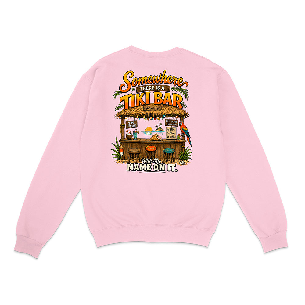 A light pink crewneck sweatshirt shown from the back, featuring a colorful graphic print of a tropical Tiki Bar with the text 'Somewhere There Is A TIKI BAR With My NAME ON It.'.