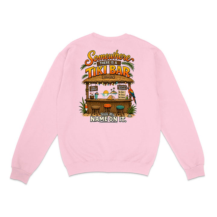 A light pink crewneck sweatshirt shown from the back, featuring a colorful graphic print of a tropical Tiki Bar with the text 'Somewhere There Is A TIKI BAR With My NAME ON It.'.