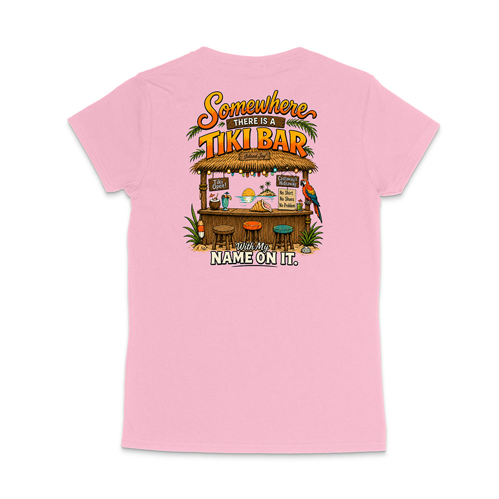 A light pink short-sleeve t-shirt shown from the back, featuring a colorful graphic of a tropical tiki bar with the text 'Somewhere there is a TIKI BAR' and 'With my NAME ON IT.'.