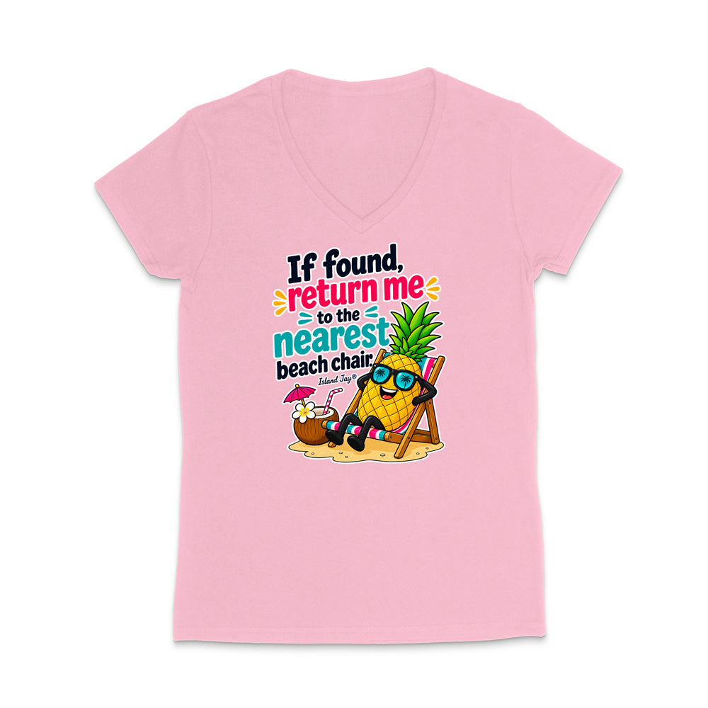 A light pink women's V-neck t-shirt featuring a colorful graphic of a pineapple character wearing sunglasses and reclining on a beach chair next to a coconut drink, with the text 'If found, return me to the nearest beach chair' printed on the front.