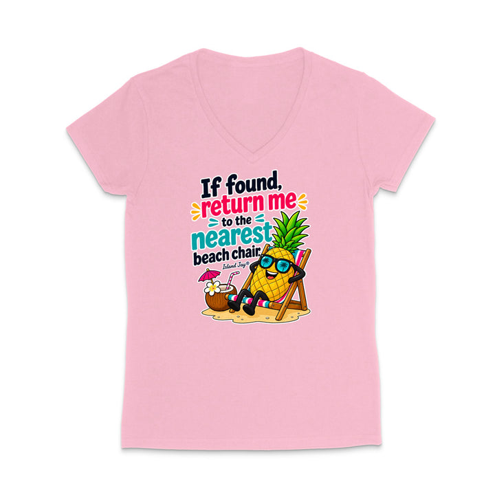 A light pink women's V-neck t-shirt featuring a colorful graphic of a pineapple character wearing sunglasses and reclining on a beach chair next to a coconut drink, with the text 'If found, return me to the nearest beach chair' printed on the front.
