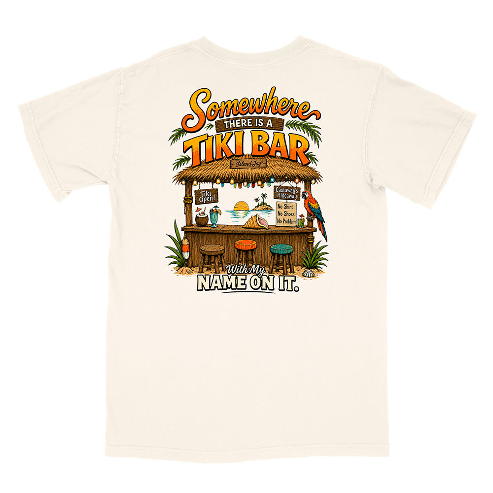 An off-white short-sleeve t-shirt with a colorful graphic print on the front depicting a tropical tiki bar, parrots, and the text 'Somewhere THERE IS A TIKI BAR With My NAME ON IT.'.