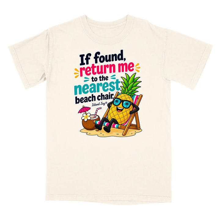 An off-white short-sleeve t-shirt with a colorful graphic of a pineapple relaxing in a beach chair next to a coconut drink, with the text 'If found, return me to the nearest beach chair. Island Joes'.