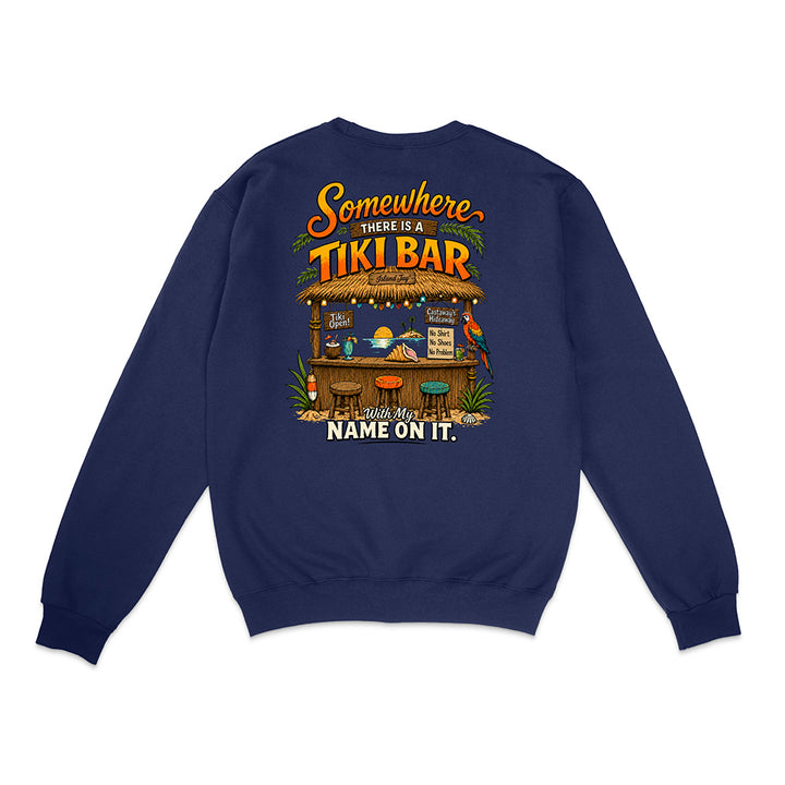 A navy blue crewneck sweatshirt shown from the back, featuring a colorful graphic of a tropical tiki bar with the text 'Somewhere THERE IS A TIKI BAR and my NAME ON IT.'.