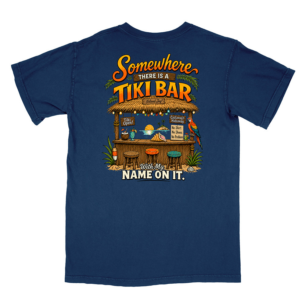 A navy blue short-sleeve t-shirt shown from the back, featuring a colorful graphic print of a tropical tiki bar with the text 'Somewhere there is a TIKI BAR' and 'Leave My NAME ON IT.'.