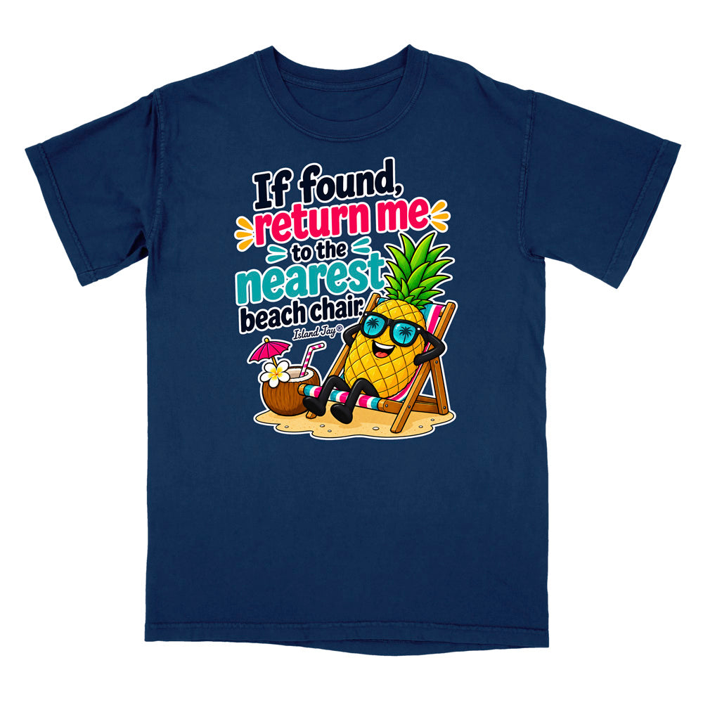 A navy blue short-sleeve t-shirt with a colorful graphic print on the front. The graphic features a cartoon pineapple wearing sunglasses and sitting in a beach chair next to a coconut drink, with the text 'If found, return me to the nearest beach chair'.