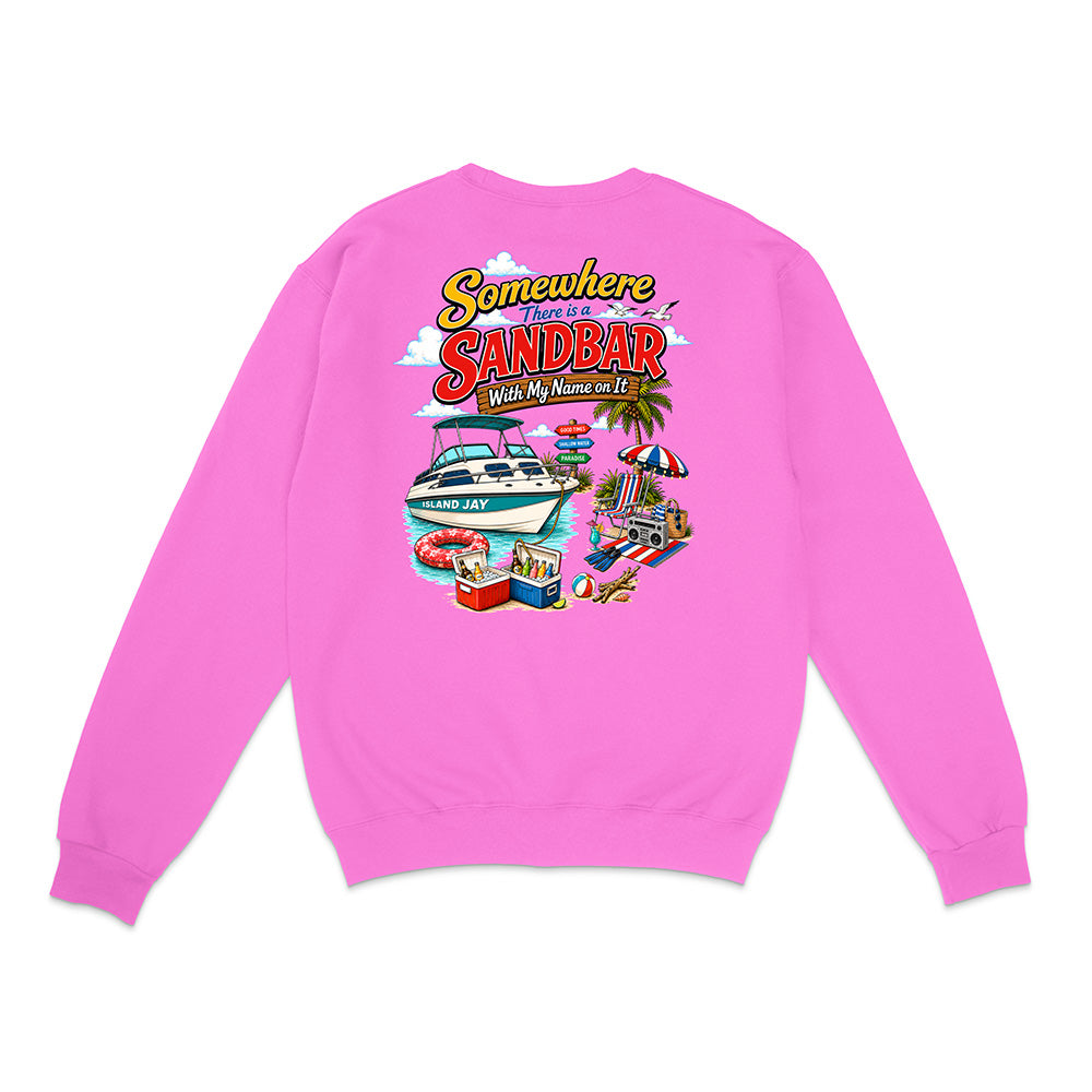 A bright pink crewneck sweatshirt shown from the back, featuring a colorful graphic print with the text 'Somewhere I've My Name Is SANDBAR' and a beach-themed illustration including a boat, palm tree, beach umbrella, and cooler.