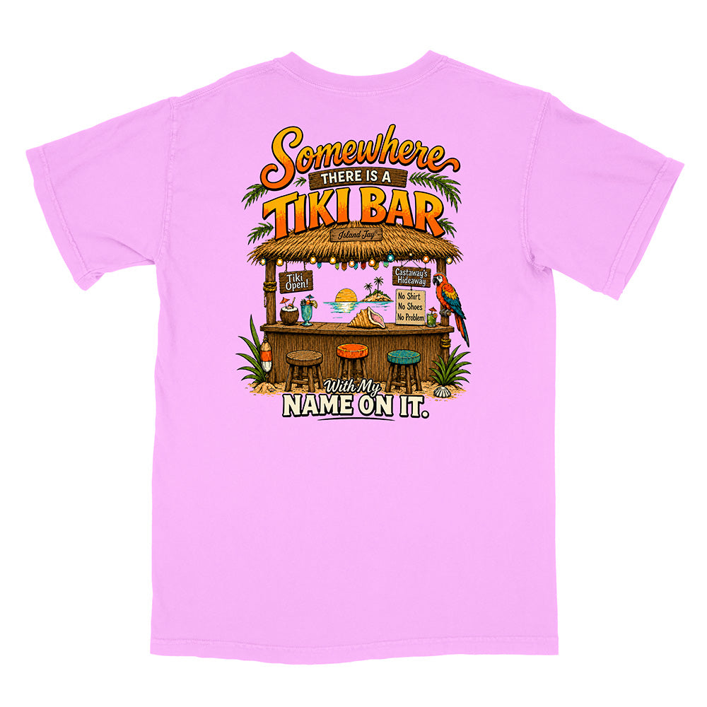 A light pink short-sleeve t-shirt shown from the back, featuring a colorful graphic of a tropical tiki bar with the text 'Somewhere THERE IS A TIKI BAR' and 'Your Name ON IT.'.