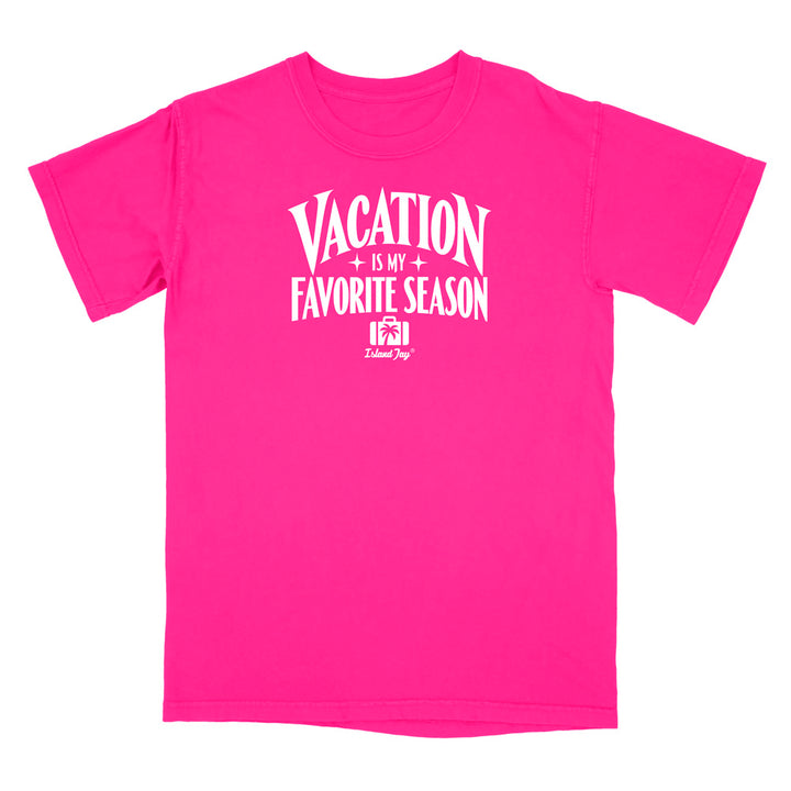 A bright pink short-sleeve t-shirt with a white graphic print on the front that reads 'VACATION IS MY FAVORITE SEASON' with a small 'Delicious Dog' logo underneath, displayed on a solid white background.