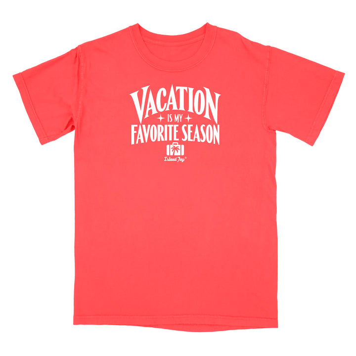 A coral red short-sleeve t-shirt with a white graphic print on the front that reads 'VACATION IS MY FAVORITE SEASON' with a small camera icon and 'Deluxe Dog' logo underneath, shown on a plain white background.