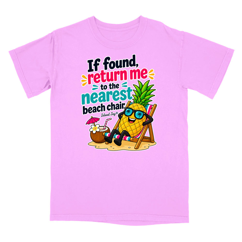 A light pink short-sleeve t-shirt with a colorful graphic on the front. The graphic features a cartoon pineapple wearing sunglasses and reclining in a beach chair next to a coconut drink, with the text 'If found, return me to the nearest beach chair' and 'Island Style!'.