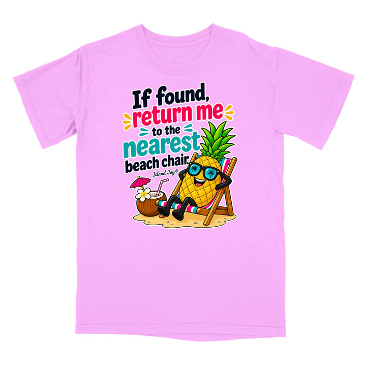 A light pink short-sleeve t-shirt with a colorful graphic on the front. The graphic features a cartoon pineapple wearing sunglasses and reclining in a beach chair next to a coconut drink, with the text 'If found, return me to the nearest beach chair' and 'Island Style!'.