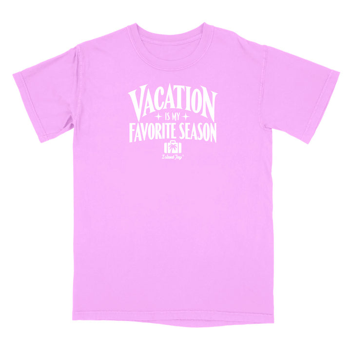 A light pink short-sleeve t-shirt with a white graphic print on the front that reads 'VACATION IS MY FAVORITE SEASON' with a small logo underneath, displayed on a solid white background.