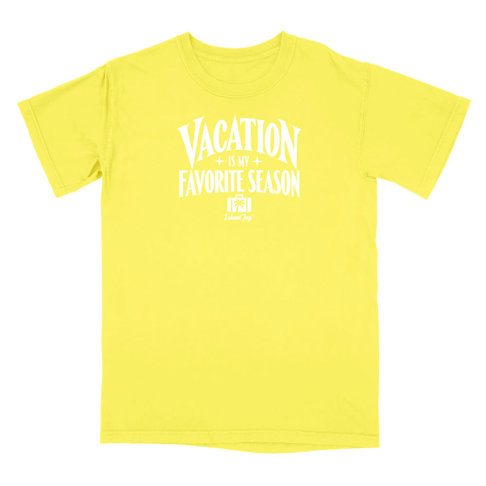 A bright yellow short-sleeve t-shirt with a white graphic print on the front that reads 'VACATION IS MY FAVORITE SEASON' with a small 'Travel Dog' logo underneath, displayed on a clean white background.