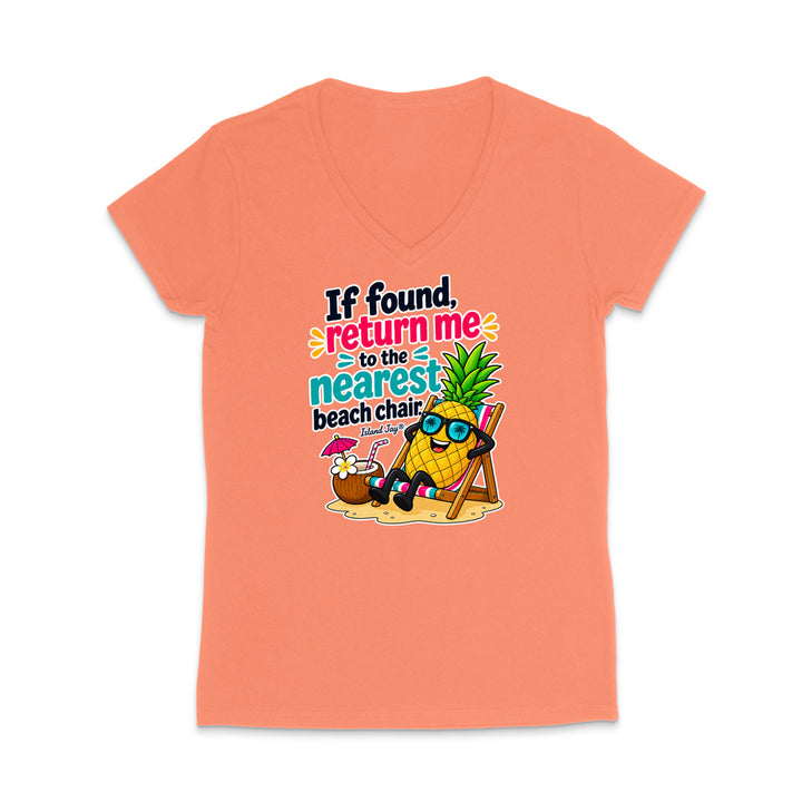 A coral pink women's V-neck t-shirt with a colorful graphic of a pineapple wearing sunglasses and relaxing in a beach chair next to a cocktail, with the text 'If found, return me to the nearest beach chair.'.