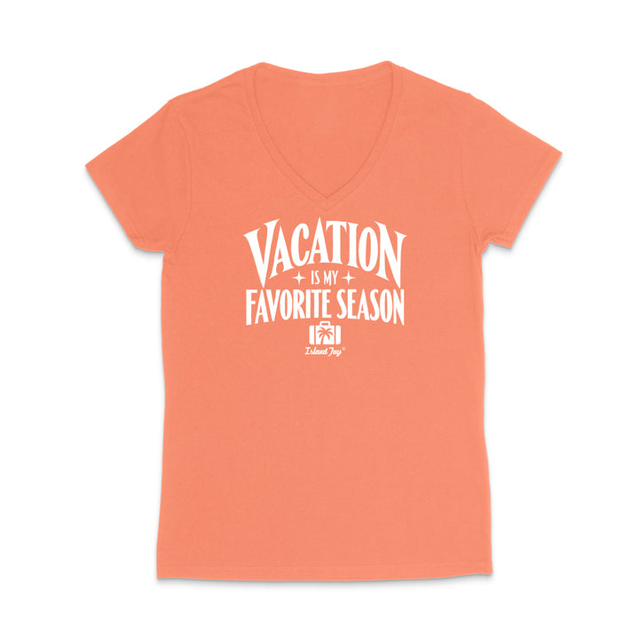 A coral orange short-sleeve V-neck t-shirt with a white graphic print on the front that reads 'VACATION IS MY FAVORITE SEASON' with a small 'Tulum Joy' logo underneath, displayed on a clean white background.