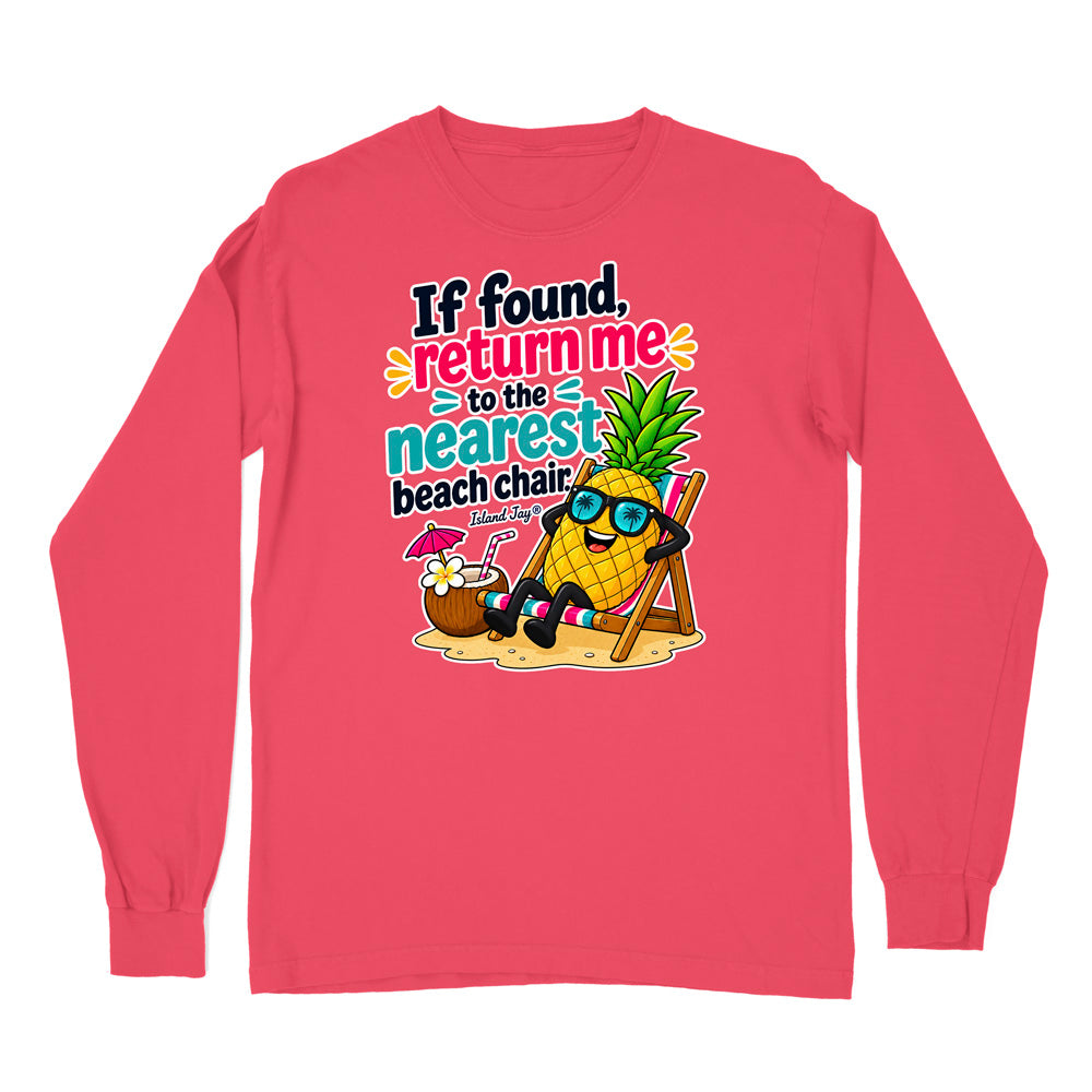 A coral pink long-sleeve t-shirt with a colorful graphic on the chest. The graphic features a cartoon pineapple wearing sunglasses and a beach chair next to a coconut drink, with the text 'If found, return me to the nearest beach chair' in black, yellow, and teal.