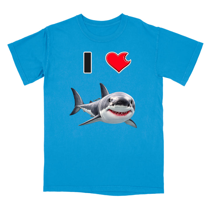 A light blue short-sleeve crewneck t-shirt featuring a graphic print of a great white shark and the text 'I' followed by a red heart and the shark, displayed on a solid white background.