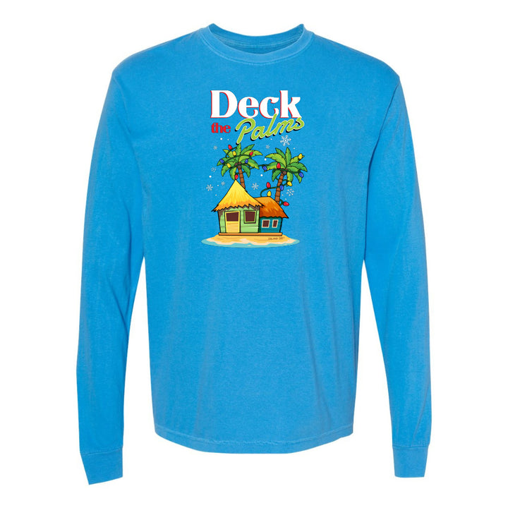 Blue long-sleeve shirt with a tropical hut and palm tree design and graphic text reading "Deck The Palms" on a white background