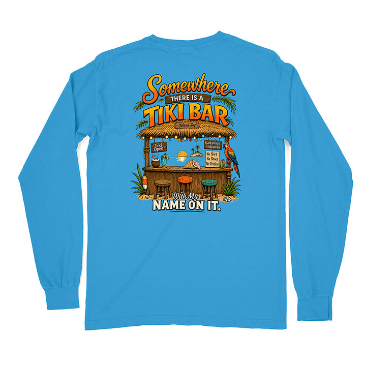 A bright blue long-sleeve t-shirt shown from the back, featuring a colorful graphic of a tropical Tiki bar with the text 'Somewhere THERE IS A TIKI BAR' and 'With My NAME ON IT.'.