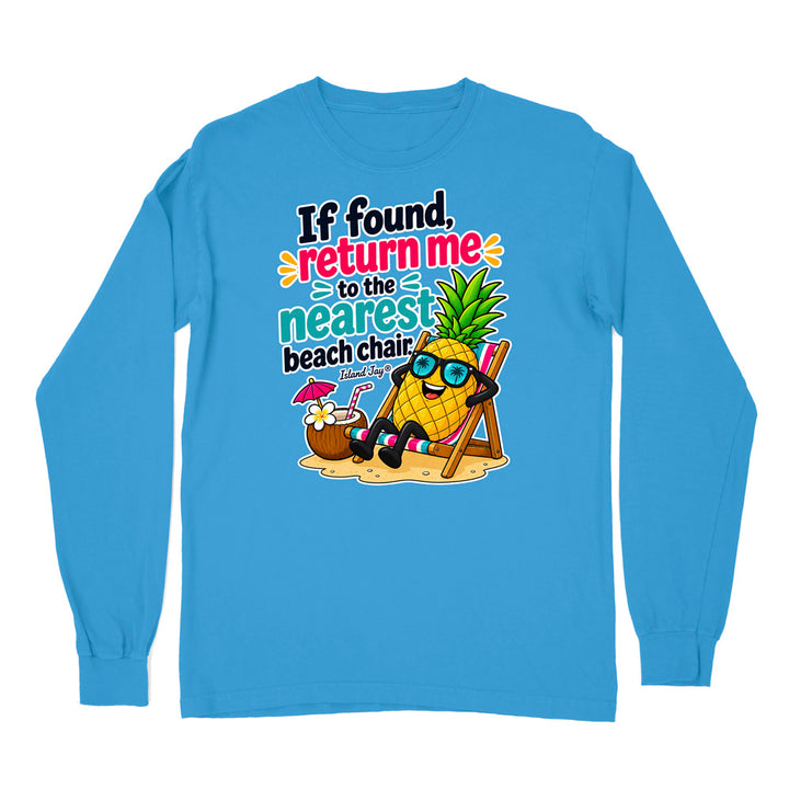 A bright blue long-sleeve t-shirt with a colorful graphic on the chest. The graphic features a cartoon pineapple wearing sunglasses and relaxing in a beach chair on the sand, next to a coconut drink, with the text 'If found, return me to the nearest beach chair.