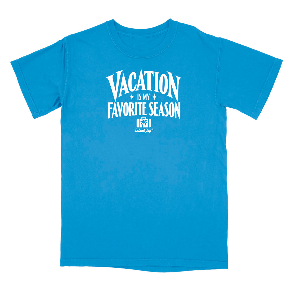 A bright blue short-sleeve t-shirt with a white graphic print on the front that reads 'VACATION IS MY FAVORITE SEASON' with a small 'Delicious Dog' logo underneath, displayed on a solid white background.
