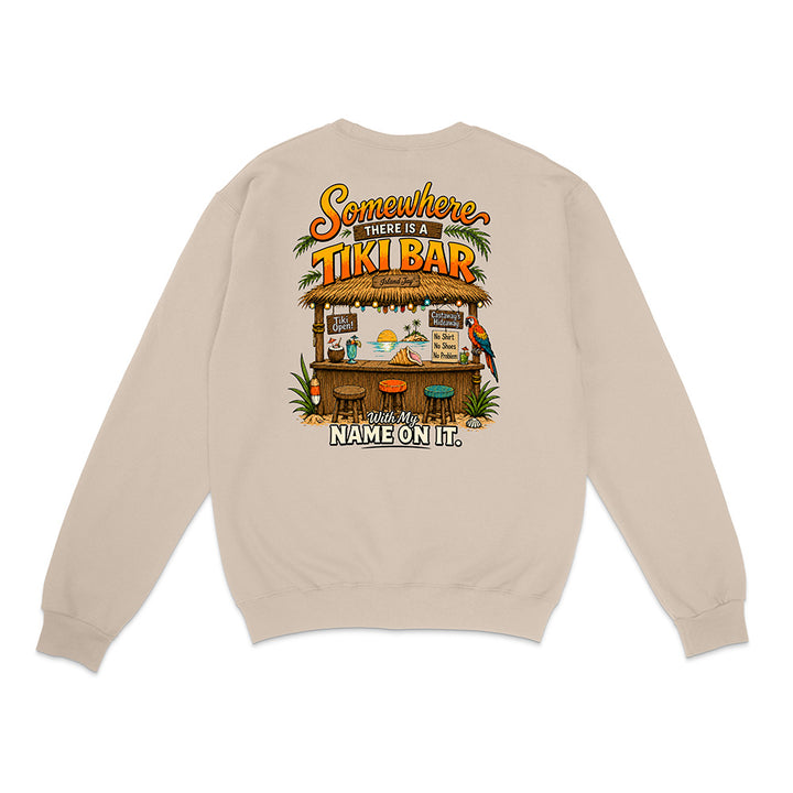 A beige crewneck sweatshirt shown from the back, featuring a colorful graphic of a tropical tiki bar with the text 'Somewhere There Is A TIKI BAR and My NAME ON IT.'.