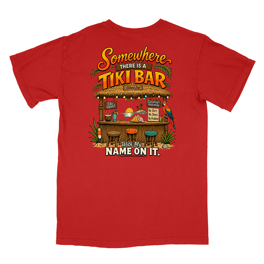 A red short-sleeve t-shirt with a colorful graphic print on the front. The graphic features a tropical tiki bar scene with the text 'Somewhere THERE IS A TIKI BAR' and 'Put My NAME ON IT.