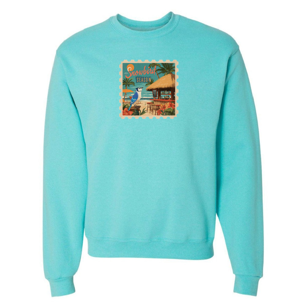 Turquoise sweatshirt with a tropical graphic on a white background