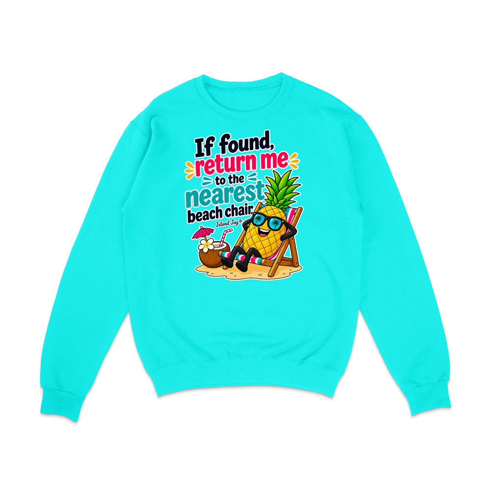 A bright turquoise crewneck sweatshirt with a colorful graphic on the front featuring a cartoon pineapple wearing sunglasses and reclining in a beach chair next to a coconut drink, with the text 'If found, return me to the nearest beach chair'.