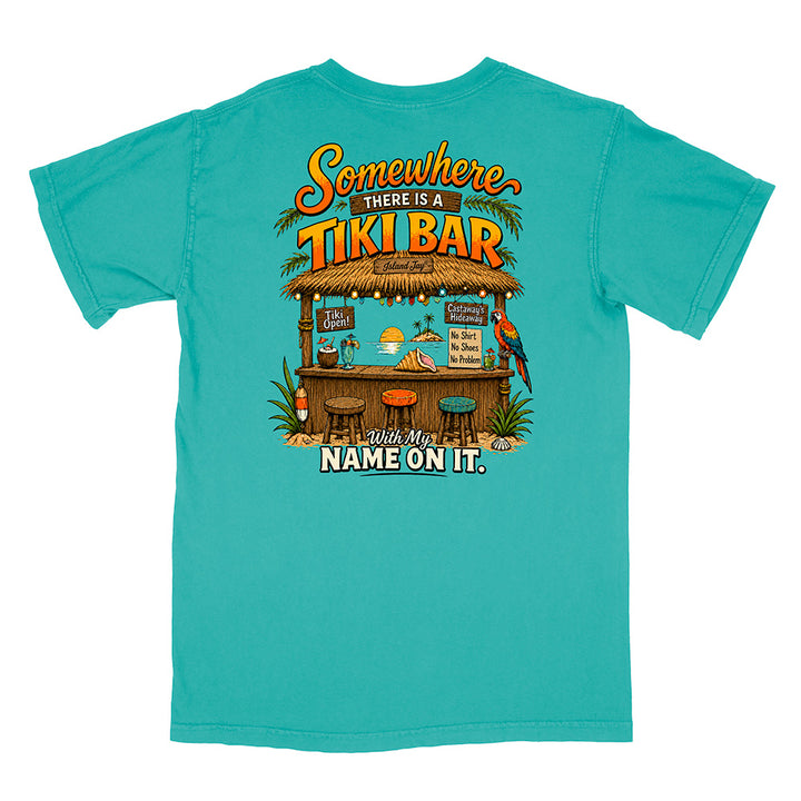 A turquoise short-sleeve t-shirt with a large graphic print on the back featuring a tropical tiki bar scene and the text 'Somewhere THERE IS A TIKI BAR With My NAME ON IT.'.