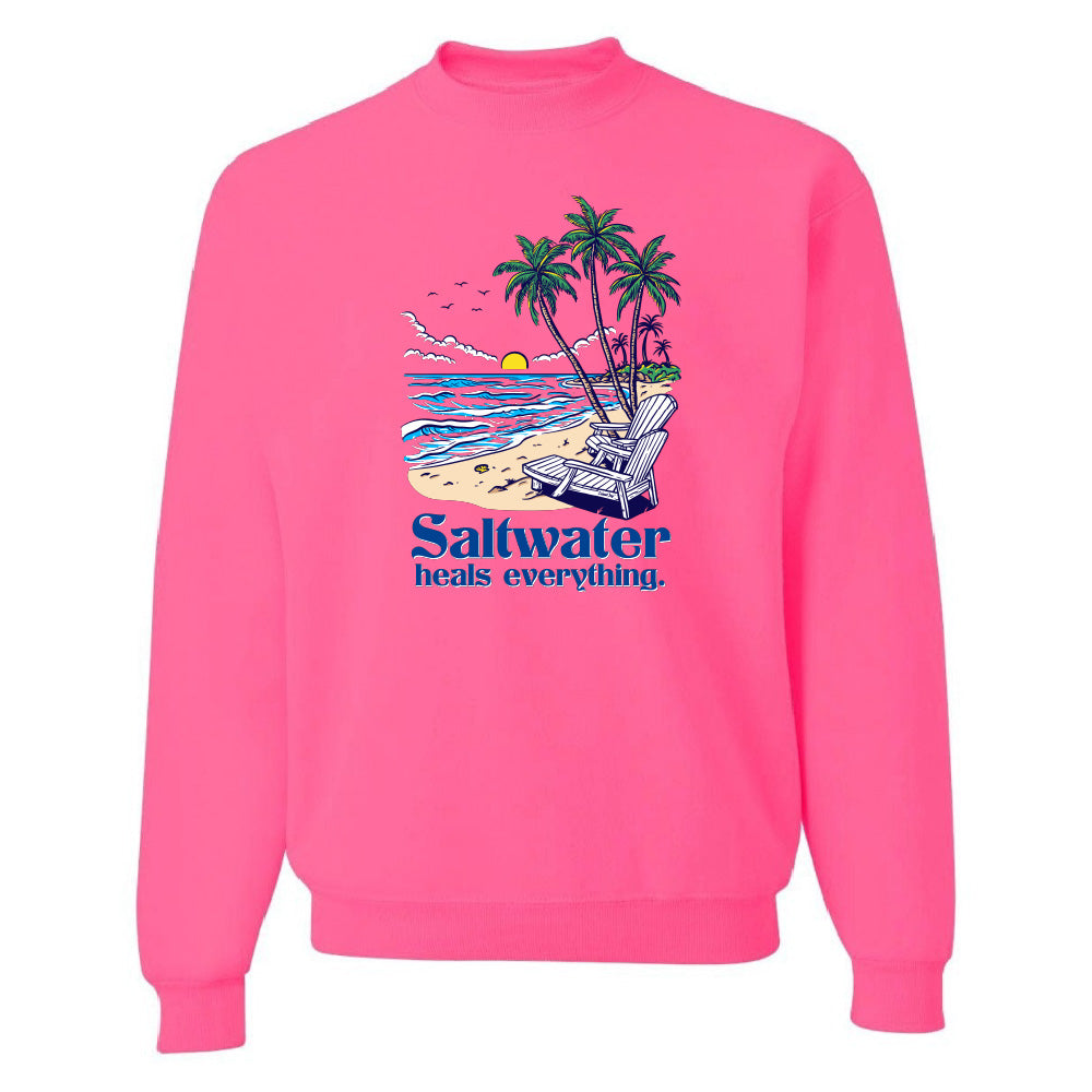 Pink sweatshirt with a beach graphic and 'Saltwater heals everything' text on a white background
