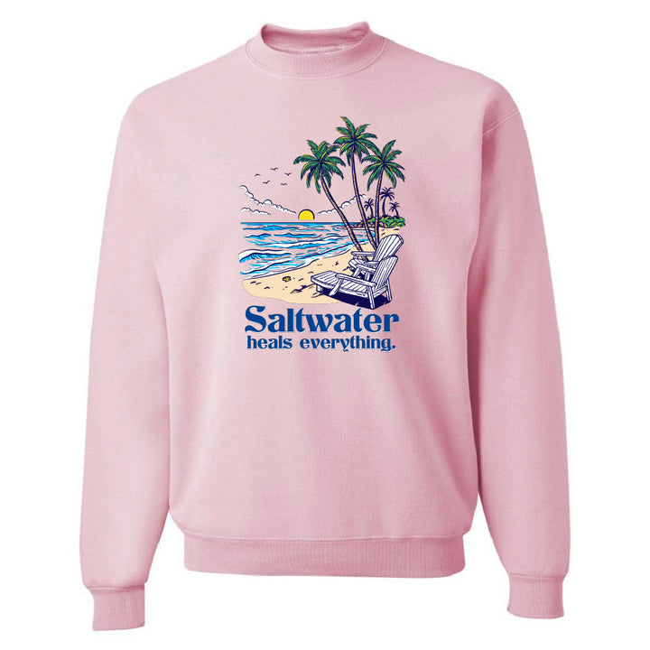 Pink sweatshirt with a beach graphic and 'Saltwater heals everything' text on a white background