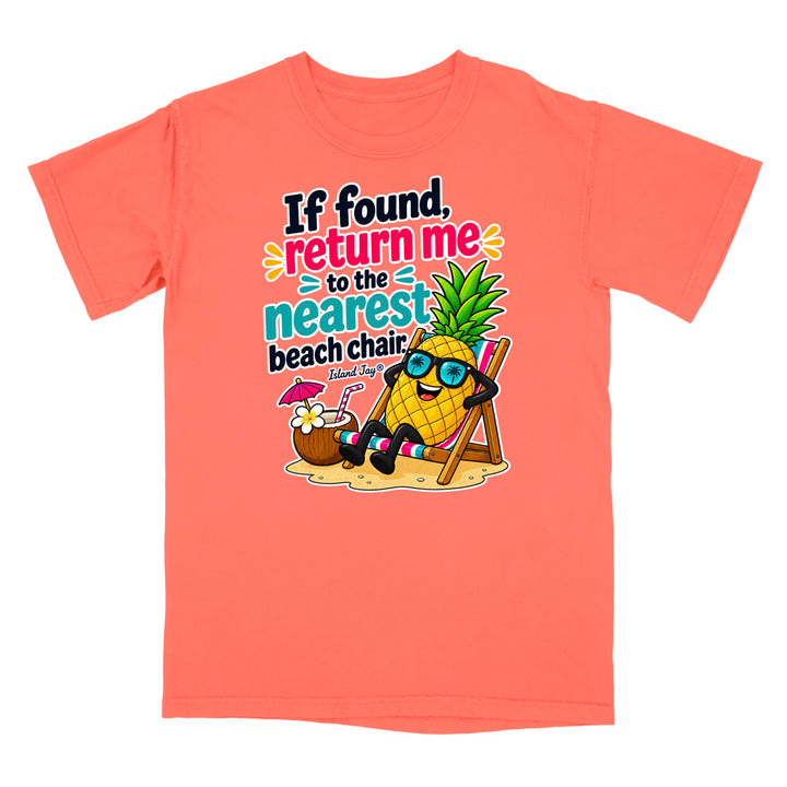 A coral orange short-sleeve t-shirt with a colorful graphic on the front. The graphic features a cartoon pineapple wearing sunglasses and relaxing in a beach chair next to a coconut drink, with the text 'If found, return me to the nearest beach chair' and 'Shark Ray'.