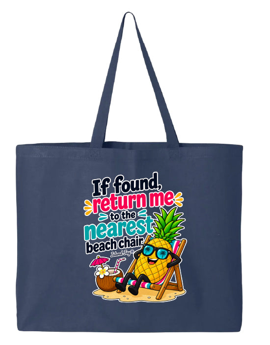 A navy blue canvas tote bag with a colorful graphic print on the front. The graphic features a cartoon pineapple wearing sunglasses and relaxing in a beach chair next to a coconut drink, with the text 'If found, return me to the nearest beach chair' in playful multicolor lettering.