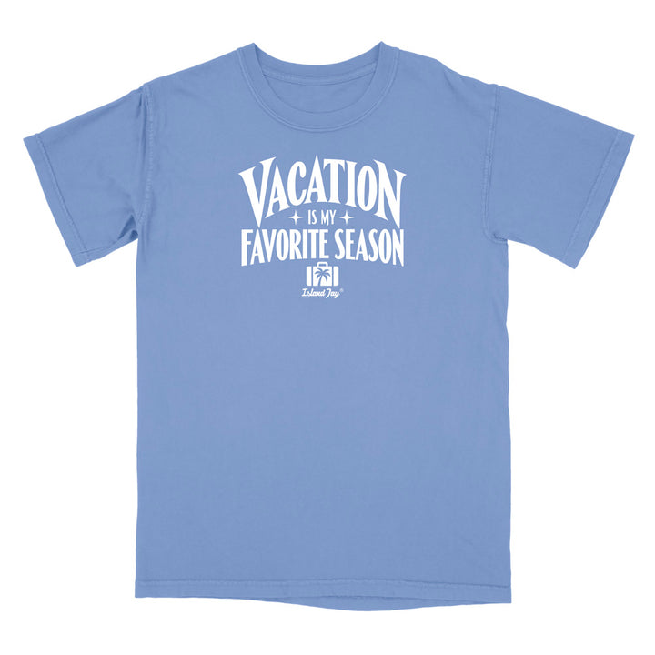 A light blue short-sleeve t-shirt with a white graphic print on the front that reads 'VACATION IS MY FAVORITE SEASON' with a small 'Kalamazoo Dog' logo underneath, displayed on a solid white background.
