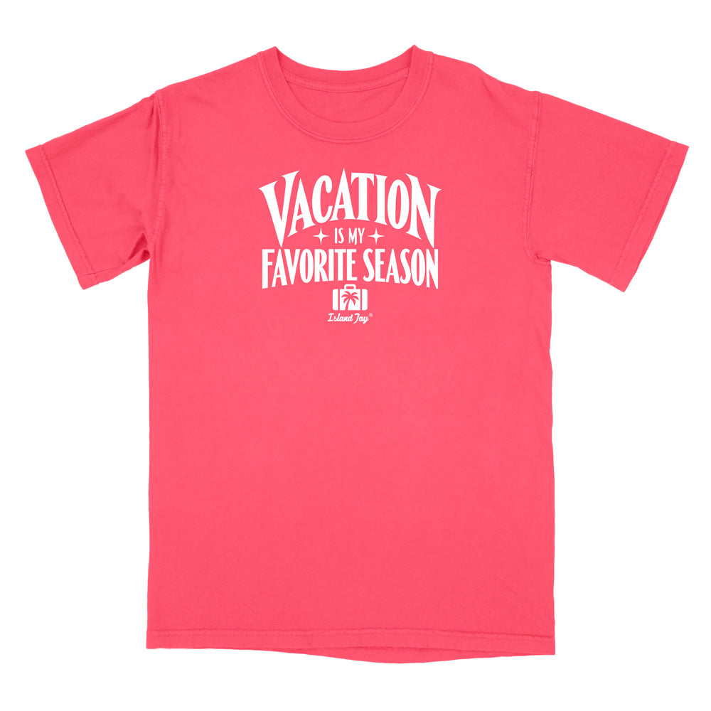 A coral pink short-sleeve t-shirt with a white graphic print on the front that reads 'VACATION IS MY FAVORITE SEASON' with a small camera icon and 'Delilah Dog' logo underneath, shown on a plain white background.