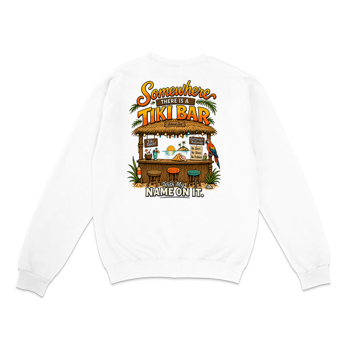 A white long-sleeve crewneck sweatshirt shown from the back, featuring a colorful graphic print of a tropical tiki bar with the text 'Somewhere There Is A TIKI BAR' and 'With My NAME ON IT.'.