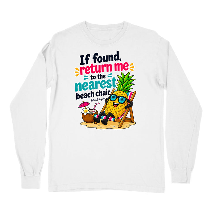 A white long-sleeve t-shirt with a colorful graphic print on the front. The graphic features a cartoon pineapple wearing sunglasses and reclining in a beach chair next to a coconut drink with a pink umbrella, with the text 'If found, return me to the nearest beach chair' and 'Island Surf Co.