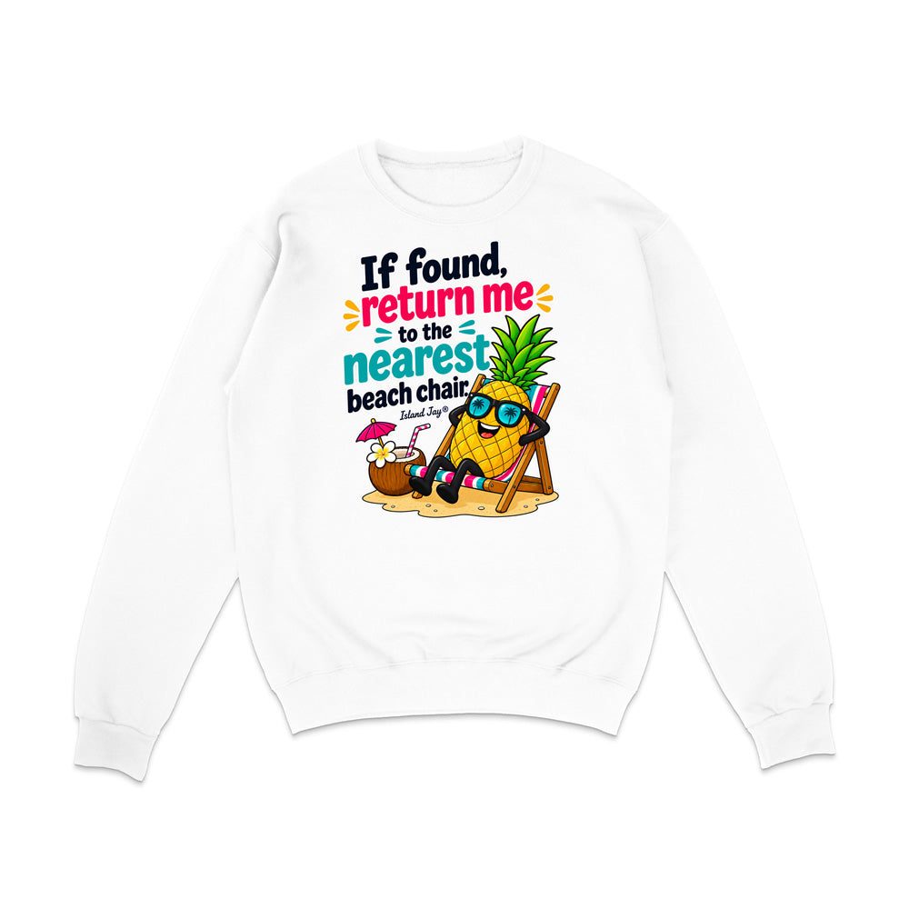 A white crewneck sweatshirt with a colorful graphic on the front showing a pineapple character wearing sunglasses and reclining on a beach chair next to a coconut shell umbrella, with the text 'If found, return me to the nearest beach chair' in a playful multicolor font.
