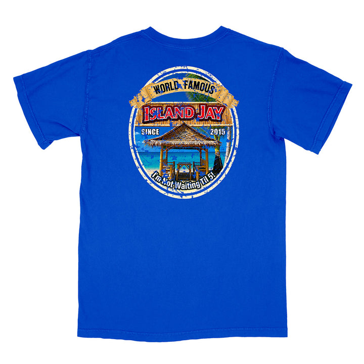 A royal blue short-sleeve t-shirt shown from the back, featuring a large circular graphic print on the center back with a beach hut, ocean, and text reading 'World Famous Island Jay' and 'I'm Not Waiting For You'.