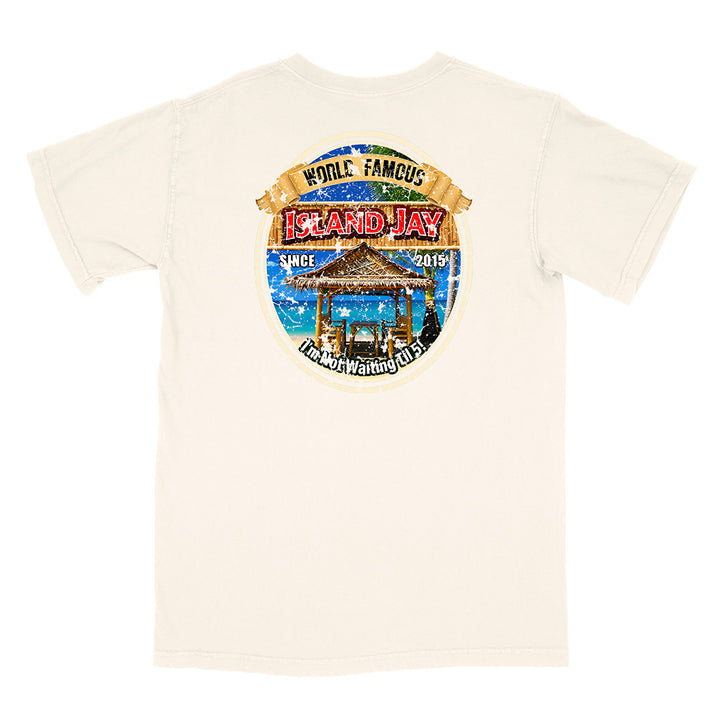 An off-white short-sleeve t-shirt with a large circular graphic print on the back. The graphic features a tropical beach scene with a gazebo, blue water, and text reading 'WORLD FAMOUS ISLAND JAY' and 'HONOLULU WAIKAI ISLAND'.
