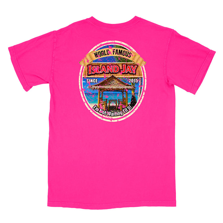 A bright pink short-sleeve t-shirt with a circular graphic print on the front. The graphic features a tropical island hula dancer scene with the text 'WORLD FAMOUS ISLAND JAY' and 'I'm Not Waiting For You'.