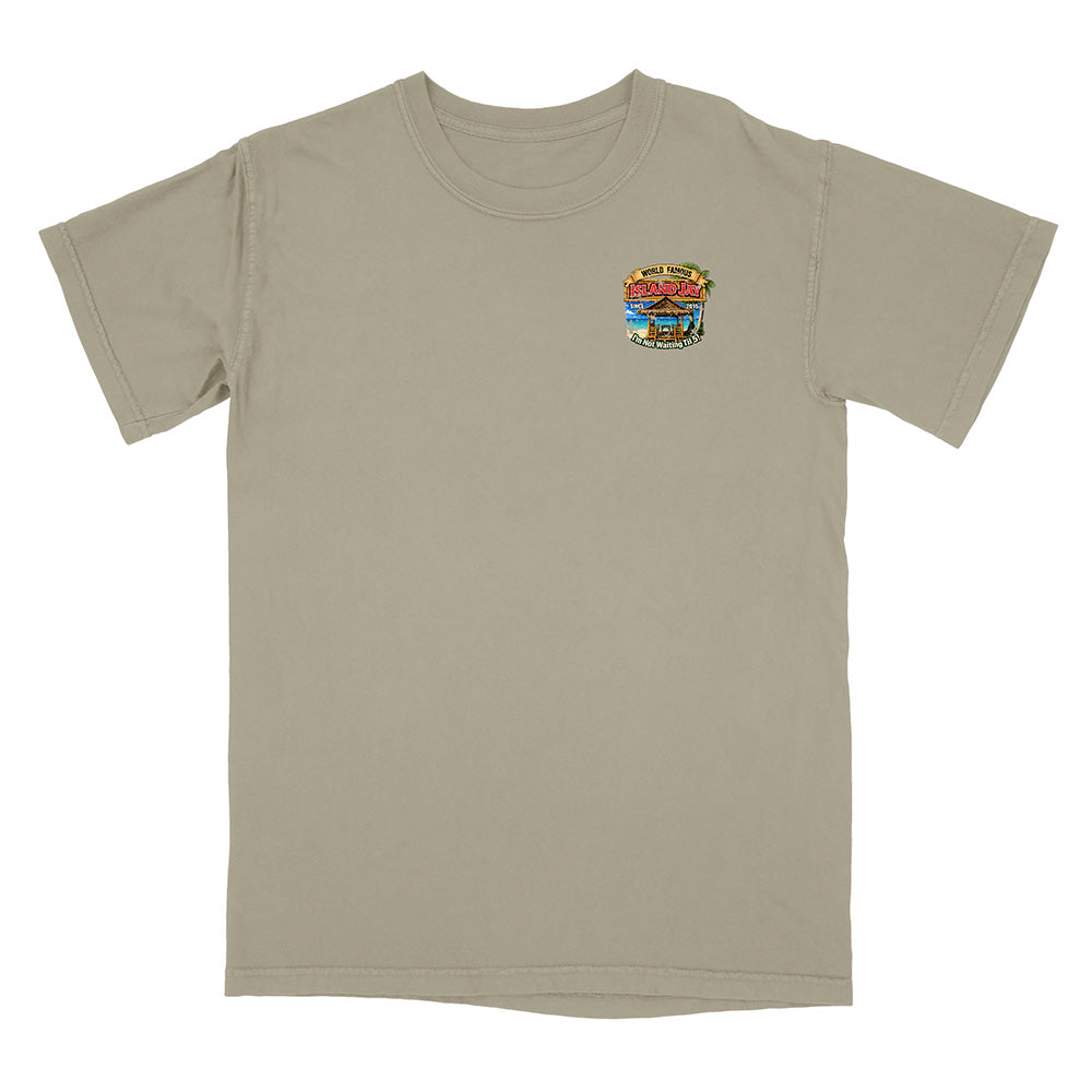 A short-sleeve crewneck t-shirt in a light khaki-beige color, featuring a small colorful graphic on the left chest depicting a beach scene with the text 'The Beach Bar'.