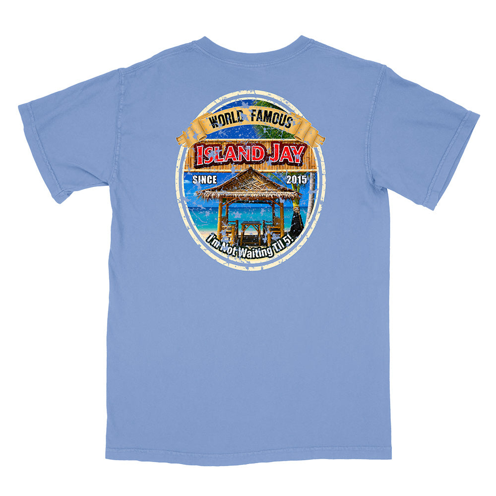 A light blue short-sleeve t-shirt with a large circular graphic on the back. The graphic features a tropical beach scene with a thatched umbrella, blue water, and a banner reading 'WORLD FAMOUS ISLAND JAY'.