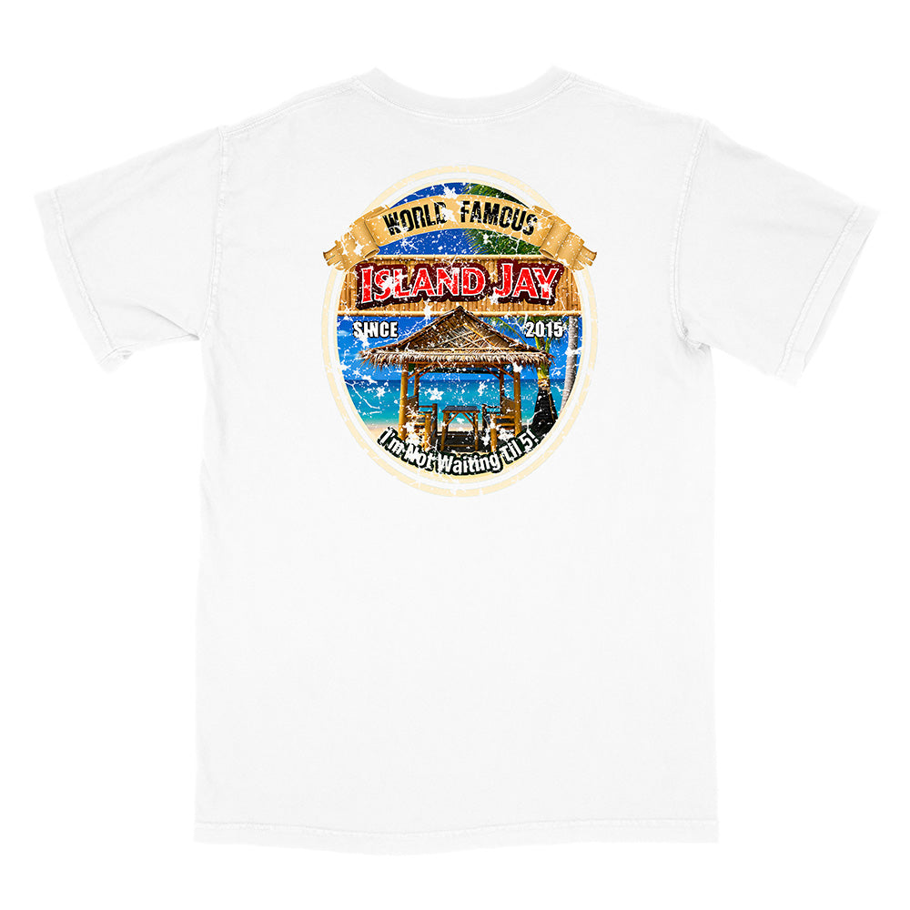 A white short-sleeve crewneck t-shirt featuring a large circular graphic print on the front. The graphic displays a tropical beach scene with a thatched-roof gazebo, blue water, and a tan banner reading 'WORLD FAMOUS ISLAND JAY'.