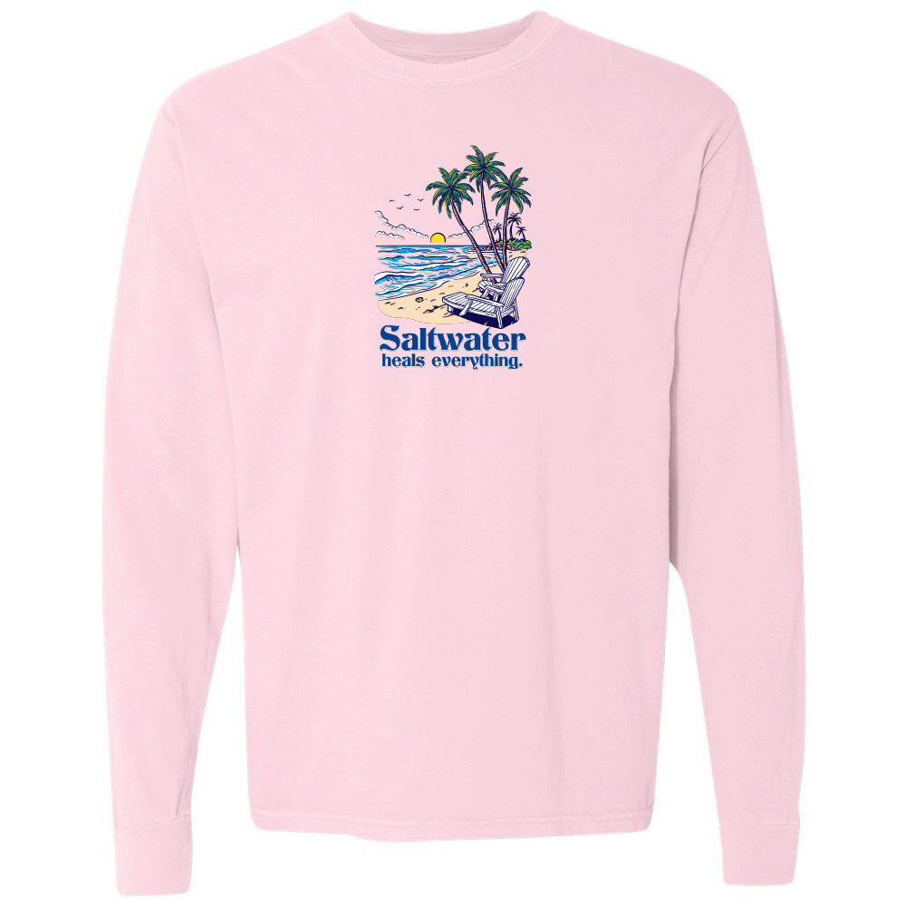 Pink long-sleeve shirt with a beach graphic and 'Saltwater heals everything' text on a white background