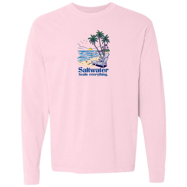 Pink long-sleeve shirt with a beach graphic and 'Saltwater heals everything' text on a white background