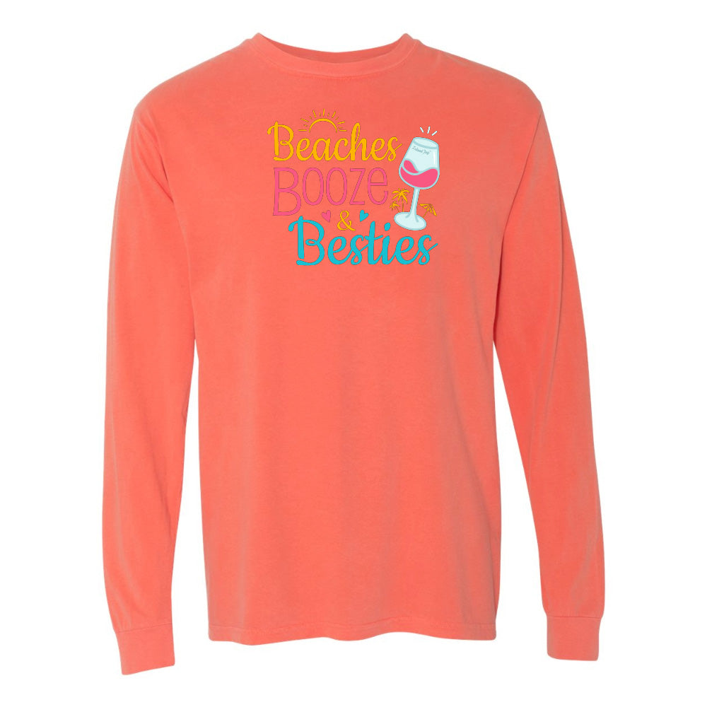 Coral long-sleeve shirt with 'Beaches Booze & Besties' text and wine glass graphic on a white background